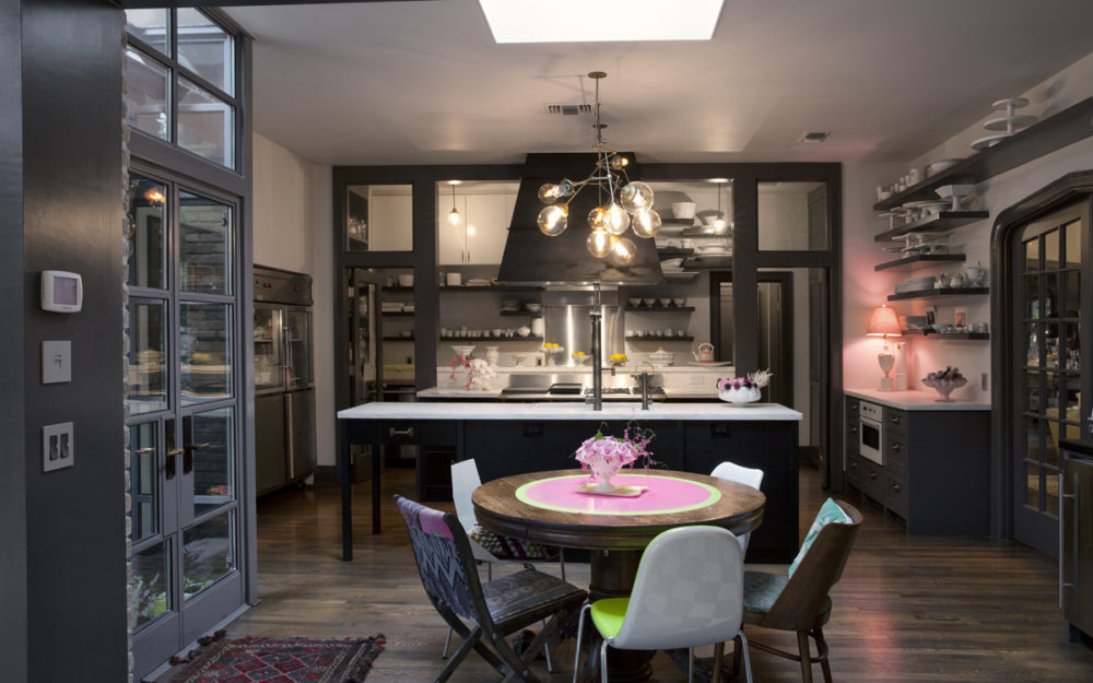 kitchen with steel and glass windows and doors, marble countertops, a french la cornue range, a copper light, shelves on the walls.